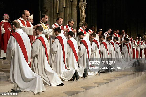 Des prêtres imposent les mains sur la tête des onze nouveaux prêtres ordonnés lors d'une messe solennelle par Mgr André Vingt-Trois, archevêque de...