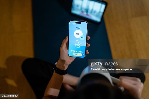close-up shot of woman tracking her water intake on her smartphone while sipping from her glass to reach goal - data intake stock pictures, royalty-free photos & images