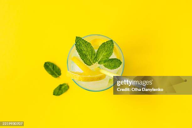 refreshing summer lemonade with lemon slices and mint on yellow background - lemon soda stock pictures, royalty-free photos & images