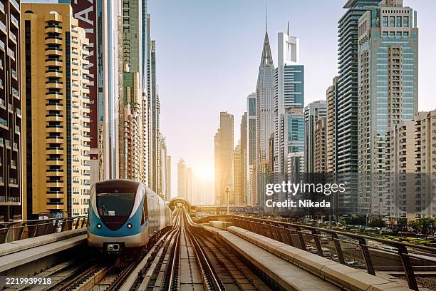 modern train on sheikh zayed road amid dubai urban landscape - dubai metro stock pictures, royalty-free photos & images