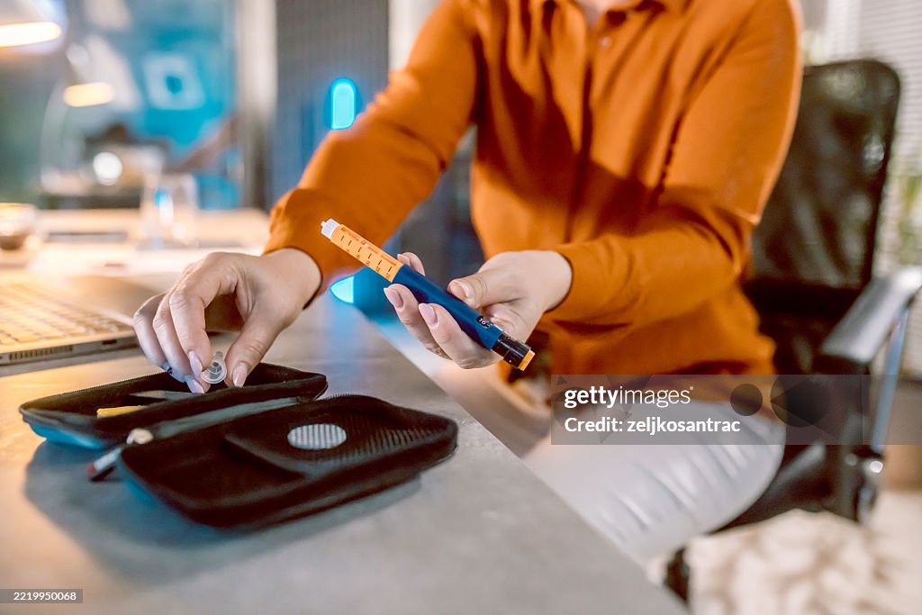 Businesswoman injecting insulin while sitting at desk in office