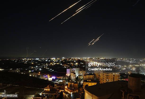 Missiles fired from Iran are seen streaking across the skies over the city of Hebron in the West Bank on June 18, 2025. Iran, which Israel continued...