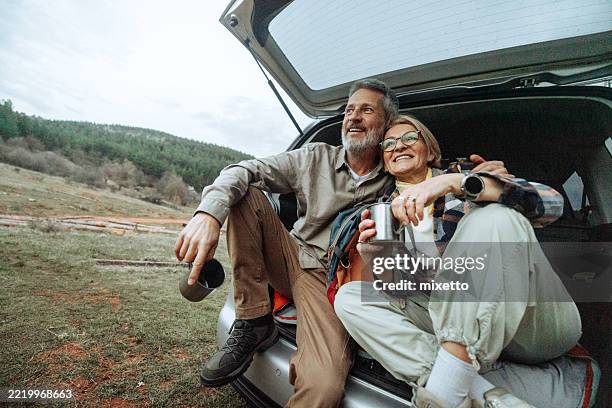 active mature couple having a warm drink after hike in nature - mature couple stock pictures, royalty-free photos & images