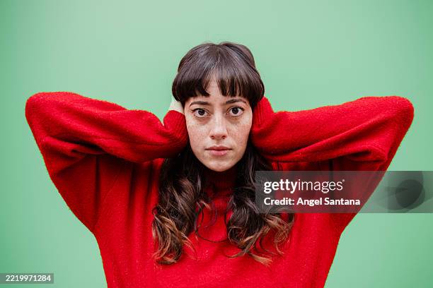 young caucasian woman covering ears with hands on green background - covering stock pictures, royalty-free photos & images