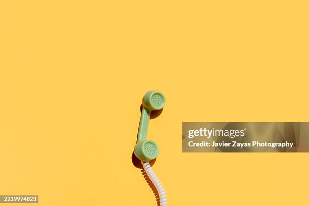 green vintage telephone handset on yellow background - telephone receiver stock pictures, royalty-free photos & images