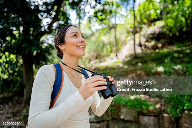 mujer viajera joven que camina y mira hacia otro lado en el parque público - mirar alrededor fotografías e imágenes de stock