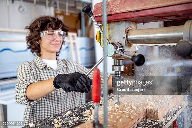 mid adult female carpenter operating drill press in a bright workshop - drill stock pictures, royalty-free photos & images