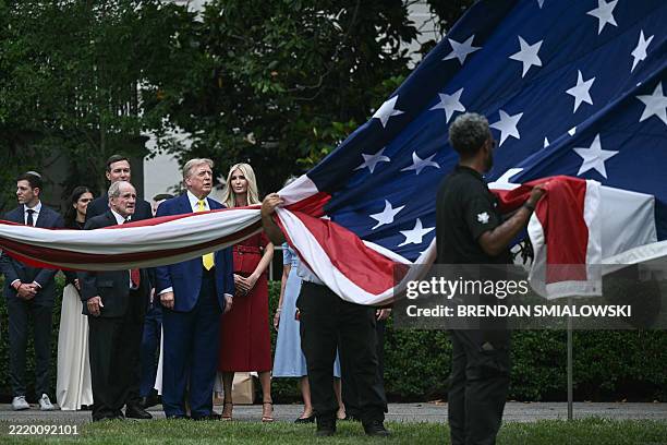 President Donald Trump, flanked by Senator James Risch and Ivanka Trump , looks on as a US flag is raised on a newly installed flagpole on the South...