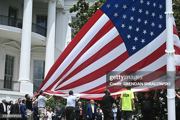 President Donald Trump looks on as a US flag is raised on a newly installed flagpole on the South Lawn of the White House in Washington, DC on June...