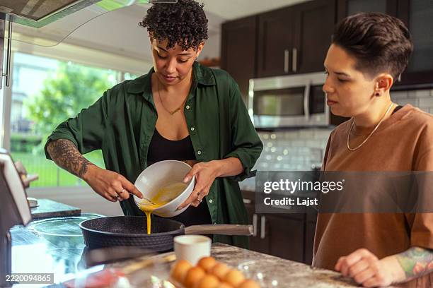 lesbian couple preparing breakfast together in the kitchen - pancake batter stock pictures, royalty-free photos & images