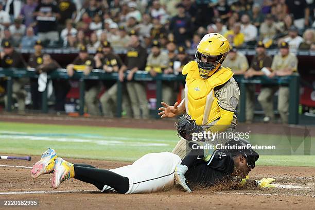 Geraldo Perdomo of the Arizona Diamondbacks dives past catcher Elias Díaz of the San Diego Padres to score the game-winning run during the ninth...