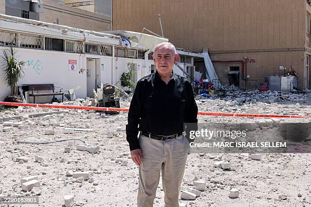 Israeli Prime Minister Benjamin Netanyahu stands amid debris outside the Soroka Hospital in the southern city of Beersheba, after it was hit by a...