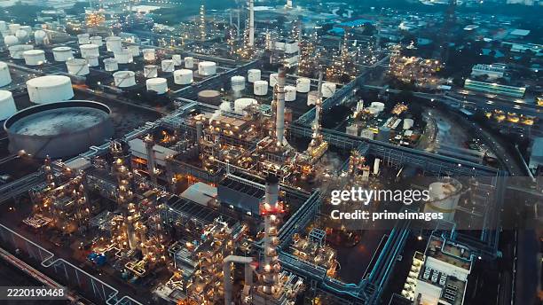 drone photo of a sprawling oil refinery facility with multiple distillation towers, storage tanks, and illuminated plant infrastructure - petrochemical plant stock pictures, royalty-free photos & images