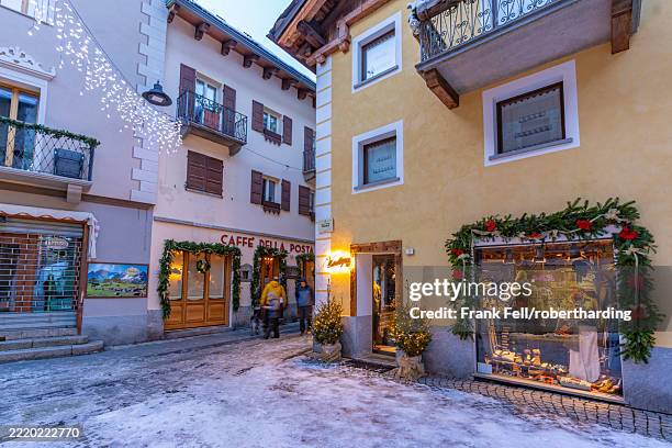 view of shops in town centre in snow in courmayeur at dusk during christmas, courmayeur, aosta valley, italian alps, italy - courmayeur stock-fotos und bilder