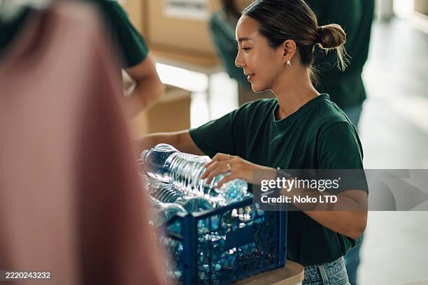 volunteer organizing plastic bottles for recycling in community center - buurthuis stockfoto's en -beelden
