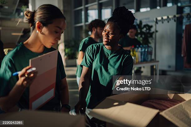 voluntarios preparando donaciones de ropa para obras de caridad en cajas de cartón - generosidad fotografías e imágenes de stock