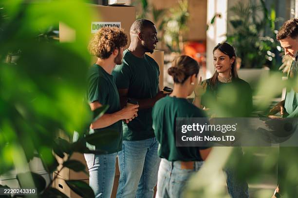 voluntarios discutiendo durante la campaña de donación en la oficina - generosidad fotografías e imágenes de stock