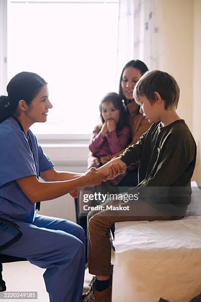 smiling female doctor examining patient in medical clinic - examination table stock pictures, royalty-free photos & images