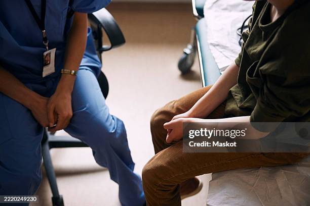 high angle view of doctor with patient sitting on examination table in clinic - general practitioner stock pictures, royalty-free photos & images