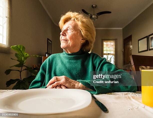 elderly woman waiting at the dining table in a quiet home - woman empty plate stock pictures, royalty-free photos & images