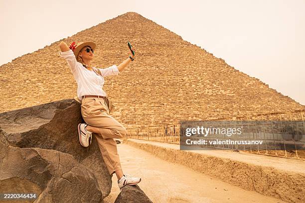 touristin frau im urlaub reist und selfie vor der großen pyramide macht. ägypten, kairo - gizeh - pyramiden von gizeh stock-fotos und bilder