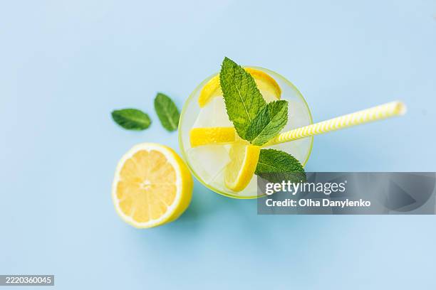 refreshing summer lemonade with lemon slices and mint on pastel blue background - citroen frisdrank stockfoto's en -beelden