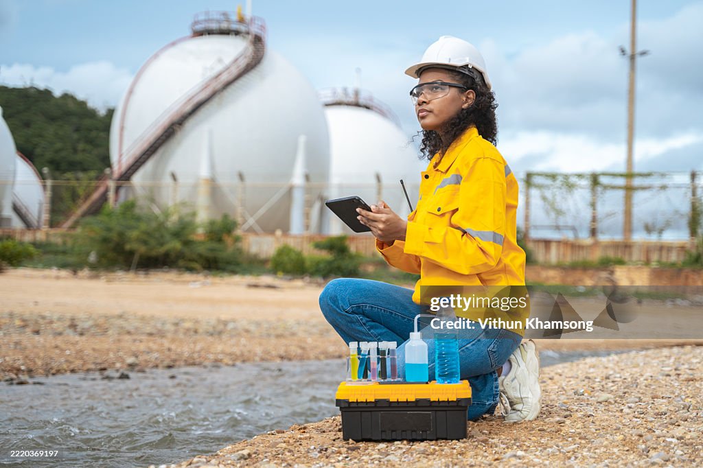 Environmental Engineer Collecting Water Samples Near Industrial Plant