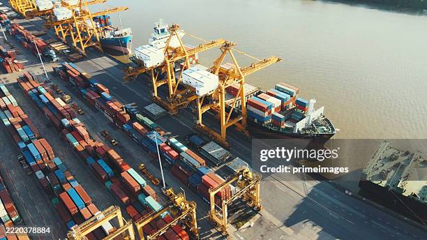 vista aérea del puerto de contenedores de singapur con buques de envío de carga y grúas en el puerto de singapur capturada desde arriba con actividad de muelle industrial - astillero fotografías e imágenes de stock
