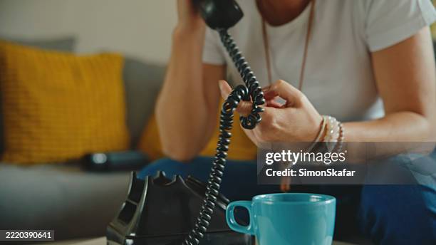 young caucasian woman using retro phone in bright modern living room with cozy decor - telefone fixo imagens e fotografias de stock