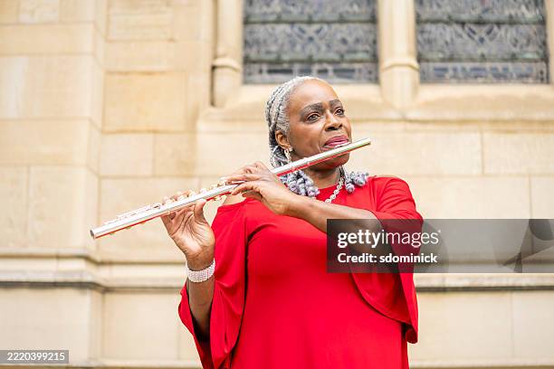 beautiful woman in red dress playing flute outdoors - flauta imagens e fotografias de stock