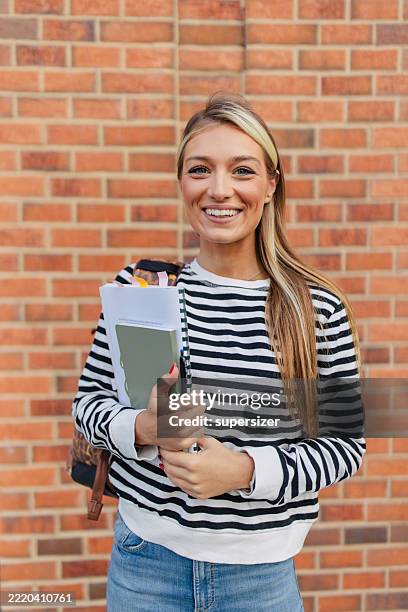 cheerful young woman poses while holding notebooks - one young woman only stock pictures, royalty-free photos & images