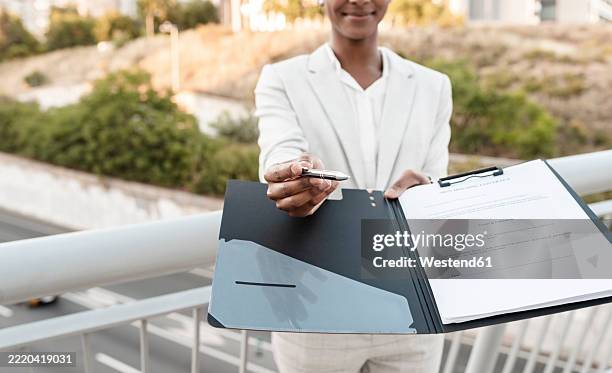 saleswoman showing contract file while standing on bridge - contract bridge stock pictures, royalty-free photos & images
