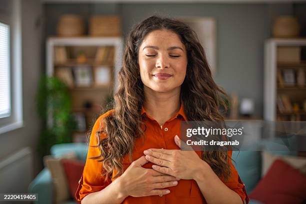 serene woman practicing mindfulness at home with eyes closed - audit stock pictures, royalty-free photos & images