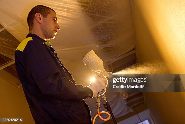 young man construction worker painting wall with spray paint - respiratory protection construction stock pictures, royalty-free photos & images
