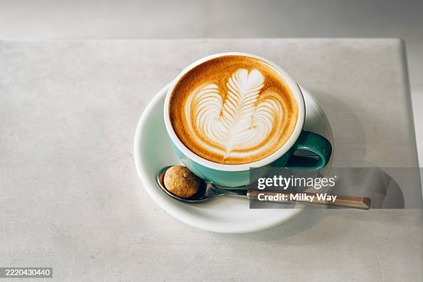 cappuccino in green cup with a beautiful latte art on stylish concrete table. - lebewesen stock-fotos und bilder