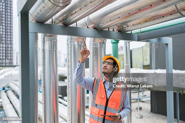 engineer pointing up to inspect an overhead pipeline system in an industrial plant - system failure stock pictures, royalty-free photos & images