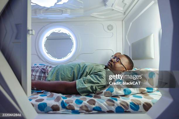 person sleeping comfortably inside a modern capsule-style sleeping pod in hostel - capsule hotel stock pictures, royalty-free photos & images