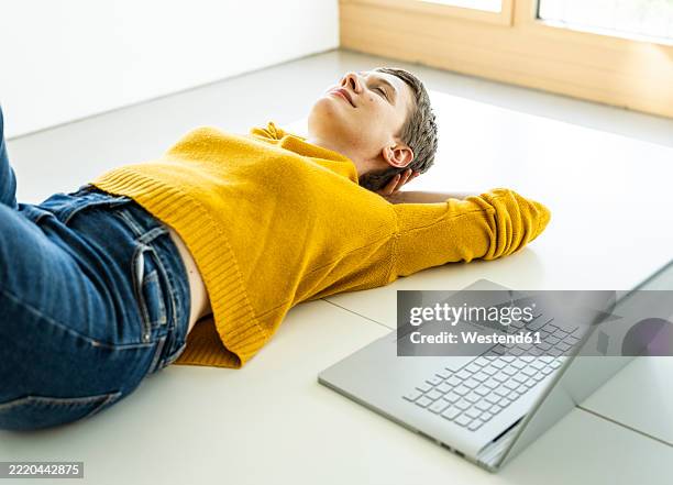 woman relaxing on the floor with a laptop in a bright office space - digital detox stock pictures, royalty-free photos & images