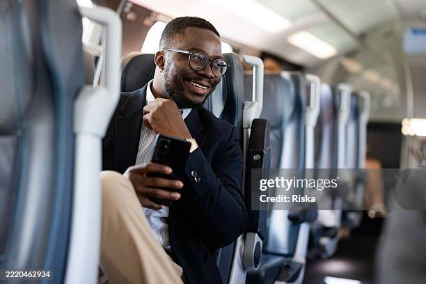 hombre de negocios disfrutando de un viaje en un tren moderno con un teléfono móvil - viaje de negocios fotografías e imágenes de stock