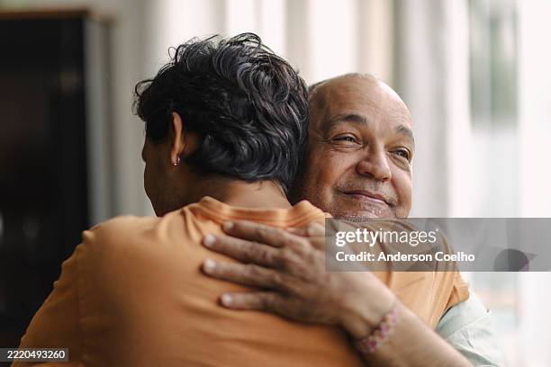 latino men hugging at home - hugging son stock pictures, royalty-free photos & images