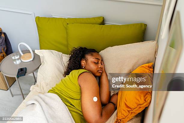 jeune femme noire se reposant paisiblement dans son lit tout en gérant le diabète de type 1 à la maison - diabète de type 1 photos et images de collection