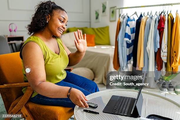 young black woman with type 1 diabetes connects virtually while managing her health in a cozy setting - type 1 diabetes stock pictures, royalty-free photos & images
