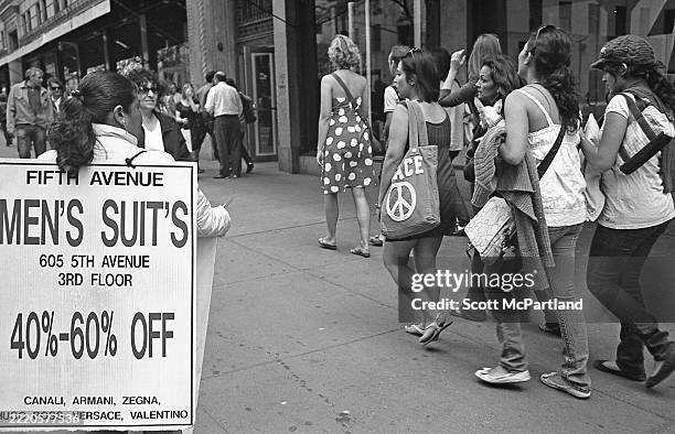 Rear view of a woman wearing a sandwich board-style advertisement for a local business as she stands outside Sak's Fifth Avenue department store and...