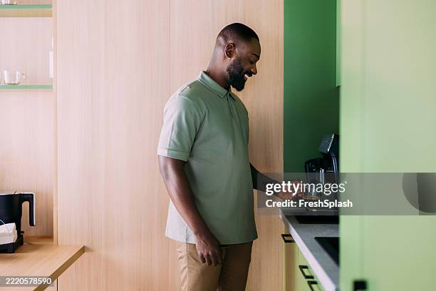 man preparing coffee in a modern kitchen using an espresso machine - man making coffee stock pictures, royalty-free photos & images