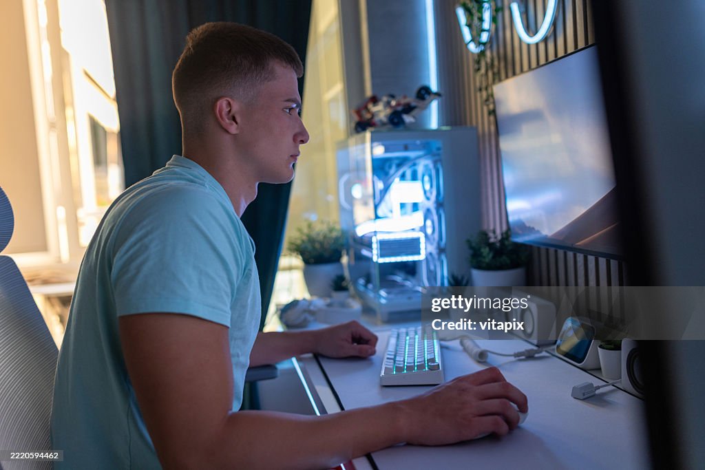 Young Man Working at Modern Gaming Setup in Stylish Home Office