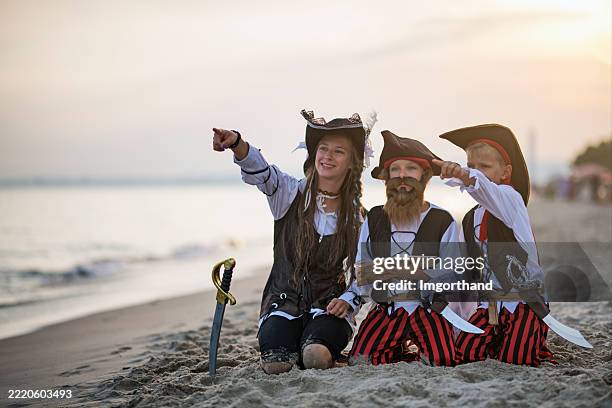 kids enjoying pirate-themed beach adventure deciphering a treasure map. - treasure hunt stock pictures, royalty-free photos & images