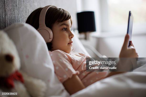 cute little girl using digital tablet in bed - people watching tv with phone stock pictures, royalty-free photos & images