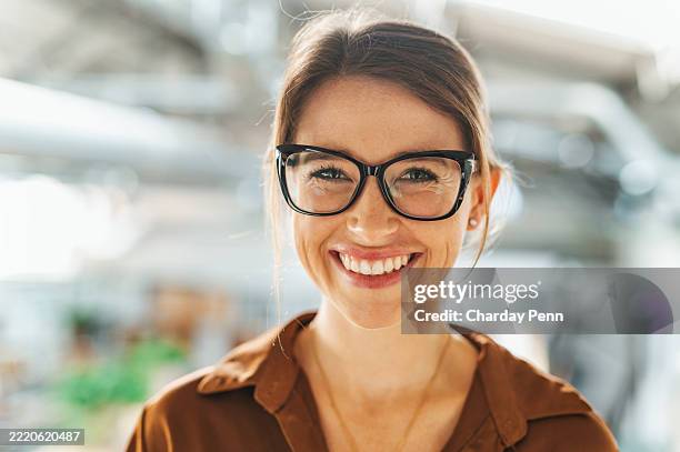 portrait of businesswoman with eyeglasses smiling cheerfully at camera in office - bril stockfoto's en -beelden