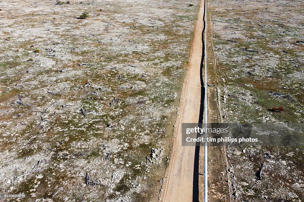 A water pipeline and access road in the sparse Australian countryside.