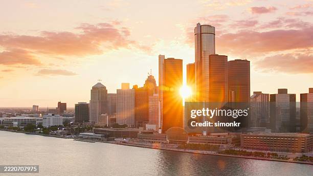 golden sunset over detroit skyline reflecting on the waterfront - detroit michigan stock pictures, royalty-free photos & images